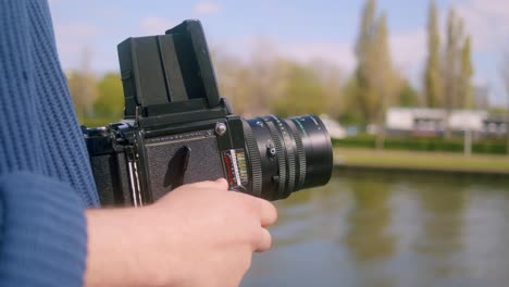 Fotógrafo-Sosteniendo-Una-Cámara-De-Película-Analógica-Mamiya-Rb67-Junto-Al-Río-En-Amsterdam,-Países-Bajos