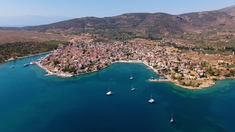 wide drone of galaxidi with sparkling blue sea and coastal town surrounded by hills