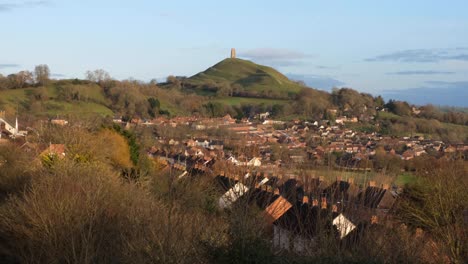 West-Country-town-of-Glastonbury-with-historic,-iconic-Glastonbury-Tor-monument-perched-atop-hill-and-houses-lining-the-streets-in-Somerset,-England