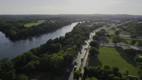 aerial view of traffic on the cesar chavez street, revealing paddlers on the colorado river, in sunny austin, usa - pan, drone shot