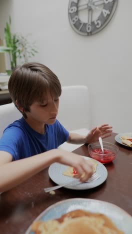 boy eating pancakes with strawberry jam