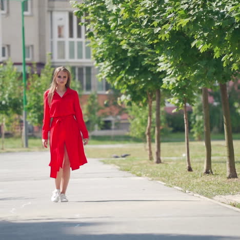 full-length portrait of a pretty model. young woman in red dress going forward in the city street. attractive girl outdoors. slow motion.