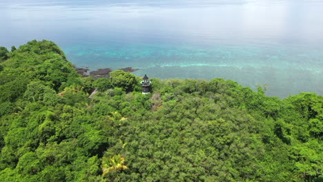 Rotating-aerial-shot-of-a-lighthouse-on-a-tree-covered-mountain-on-an-island-off-Madagascar