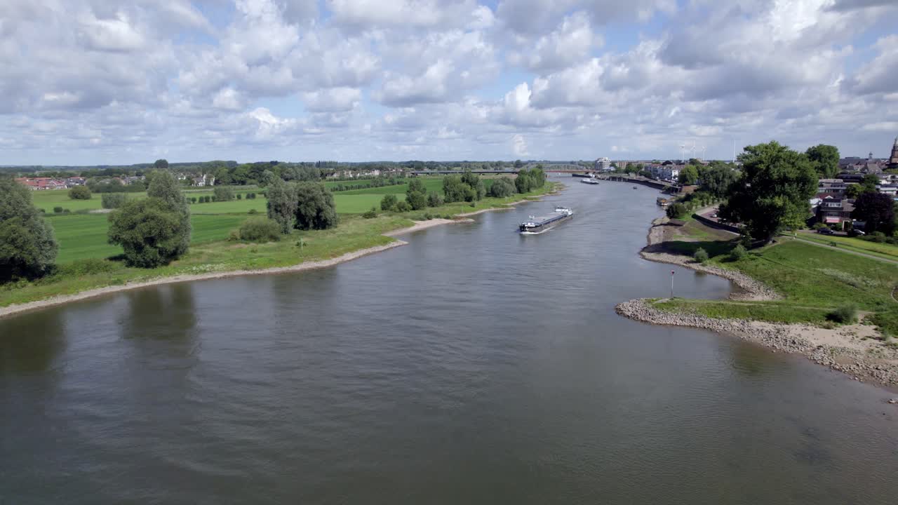 Aerial approach of transportation vessel on the river IJssel with floodplains in the background on a sunny day
