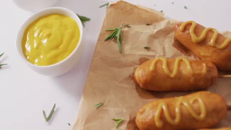 video of corn dogs with dips on a white surface