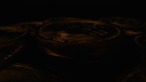 Bitcoins-Auf-Einer-Sich-Drehenden-Plattform,-Beleuchtet-Von-Einem-Flackerndem-Licht-Vor-Einem-Dunklen-Hintergrund---Nahaufnahme