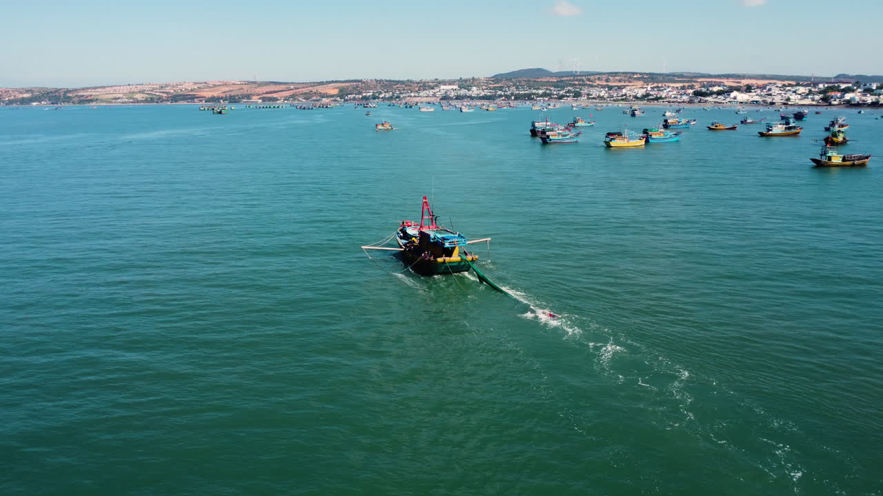 항만 근처에서 항해하는 동안 공중, 트롤선이 그물을 뒤로 끌고 있습니다.