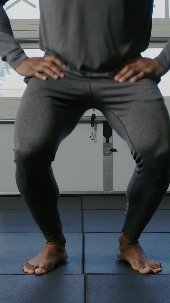 Vertical video: Starting standing for exercise, male pulsing hips in leggings on mats, garage track