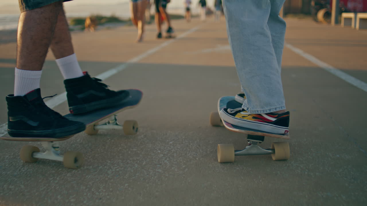 patinadores de primer plano piernas montando longboards carretera de asfalto. pareja desconocida moviéndose rápido