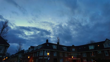 Zeitraffer-Der-Häuser-Am-Koekoeksplein-Amsterdam-Noord-Vorort-Mit-Ziehenden-Wolken-Und-Eingeschalteten-Laternenpfählen