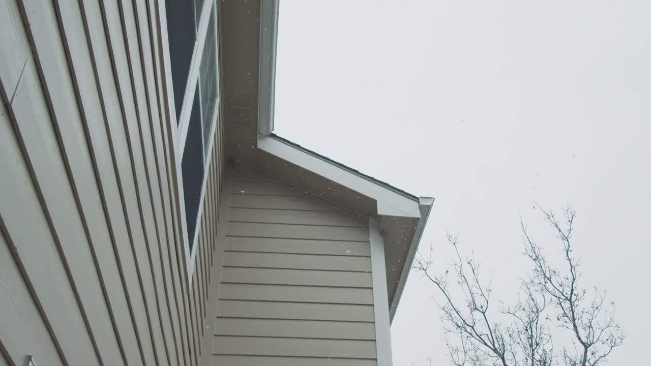 Snowflakes falling next to american house wooden facade, slow motion