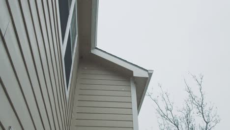 snowflakes falling next to american house wooden facade, slow motion