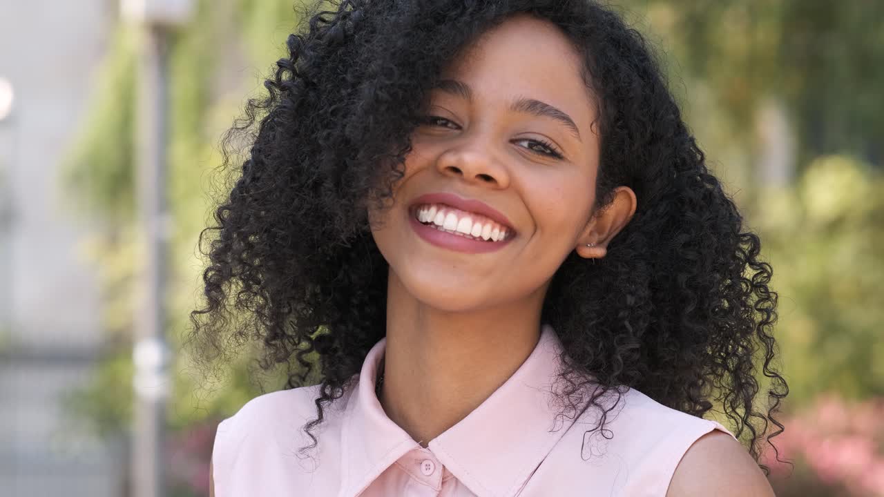 Contented black woman smiling in city during daytime