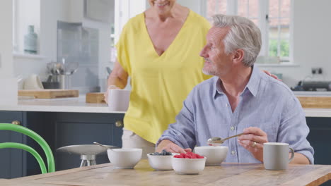 Pareja-De-Jubilados-Sentados-Alrededor-De-La-Mesa-En-Casa-Desayunando-Saludablemente-Con-Fruta-Fresca-Juntos