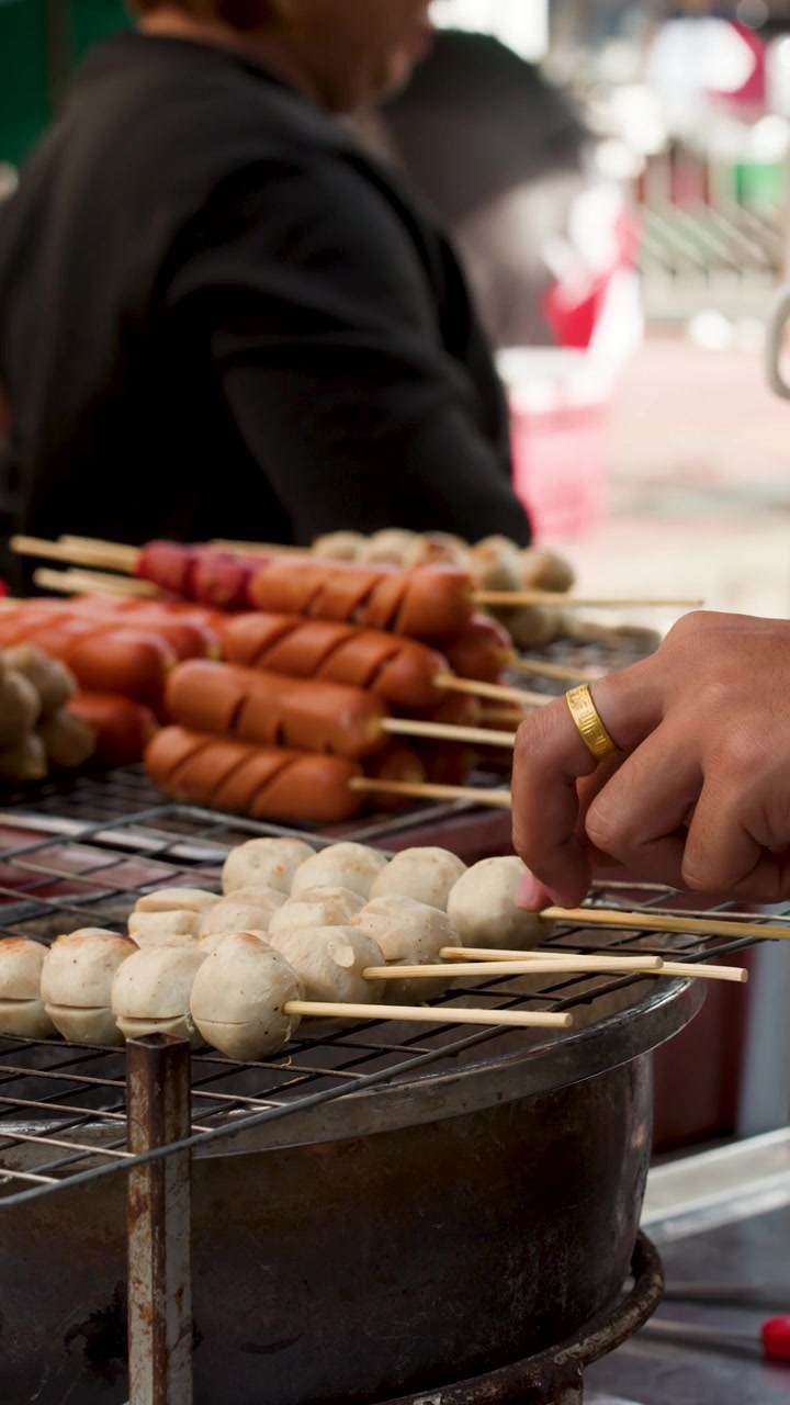 Close-up penjual kaki lima memanggang sate bakso dan sosis di Pasar Bunga Bangkok