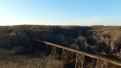 aerial shot pushing forward and panning down to the pope lick railroad trestle in louisville kentucky at sunset