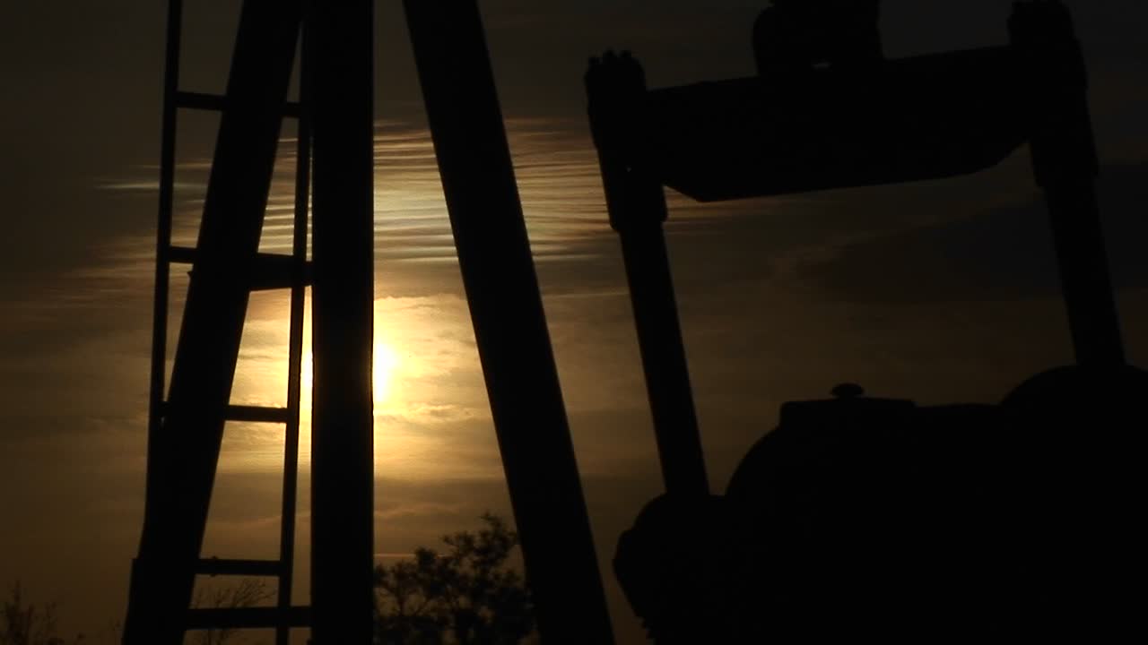 뉴멕시코 사막에서 회전하는 실루엣 오일 펌프의 근접 촬영