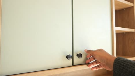 person opening a light green painted cabinet door