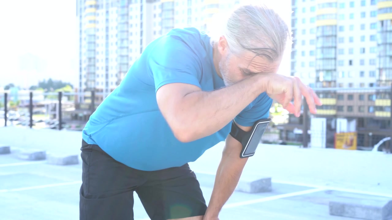 Mature Man Resting After Running on Urban Rooftop