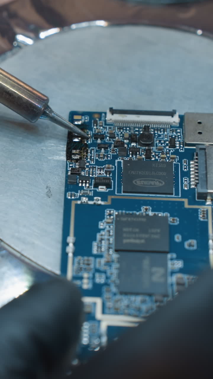 una vista de cerca de un soldador y una placa de circuitos impresos (pcb) en una superficie metálica, con alguien trabajando en el circuito con soldador