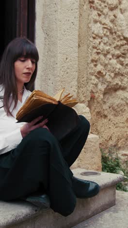 religious young woman reading the bible book at the entrance of the church