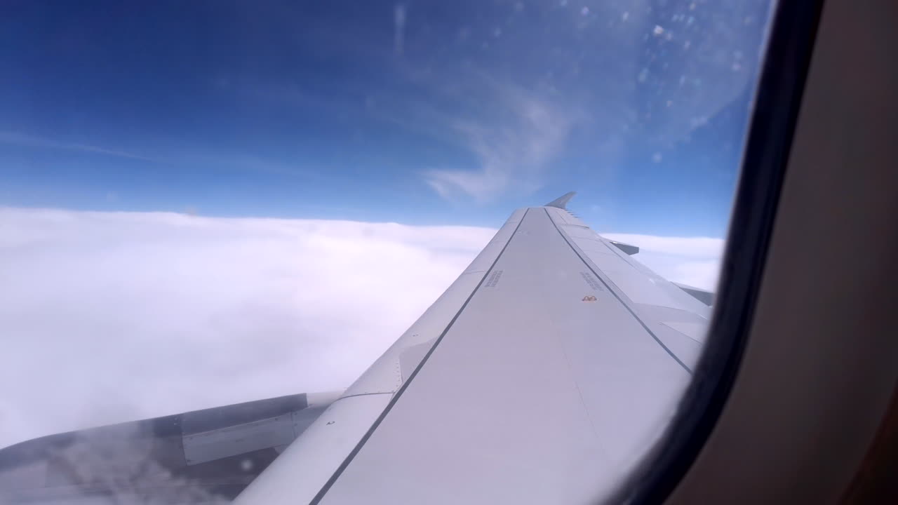 View from an airplane window of the aircraft wing in the clouds