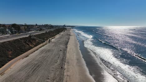 aerial view over the waves crashing against the shoreline along the beaches of carlsbad, california, usa with sunlight falling on the sea water