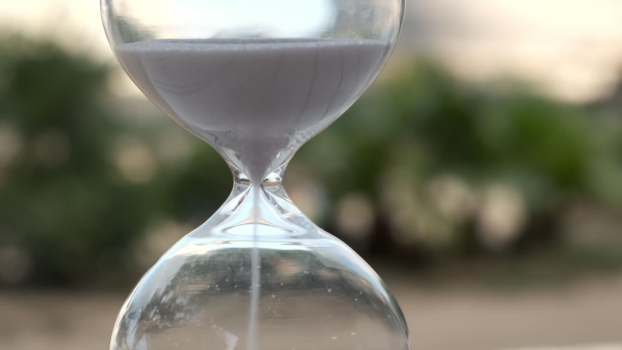 Hourglass as time passing on wooden table with bokeh background