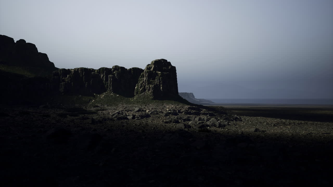 Rocky terrain under a misty sky at dusk near the coastline