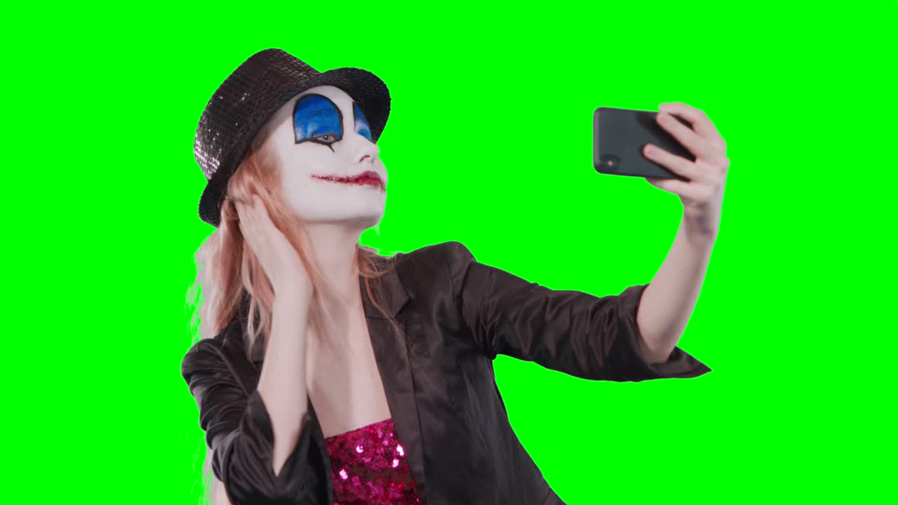 el payaso de halloween se maquilla tomando una selfie con su teléfono móvil.
