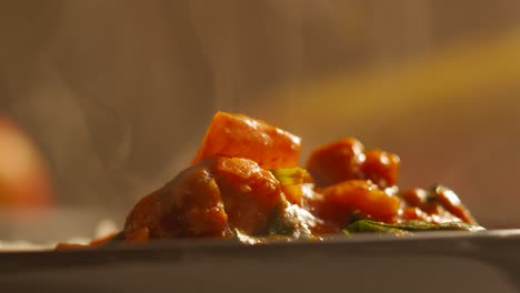 Side-View-of-Vegetable-Tikka-Masala-Curry-Dinner-in-a-Bowl-with-Steam-Rising-in-Ultra-Slow-Motion-with-Cauliflower,-Spinach,-Peppers,-Onions---4K-Footage