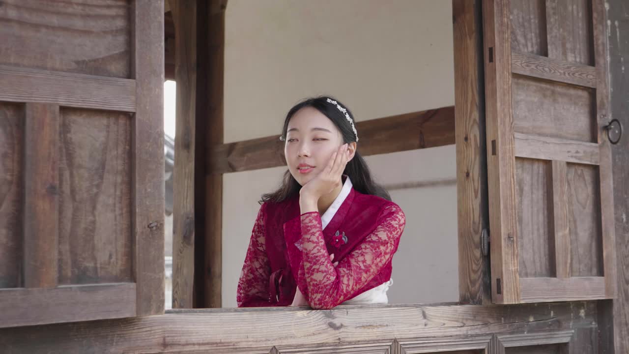 Hymyilevä nuori naismalli hanbok-asussa perinteisessä korealaisessa talossa