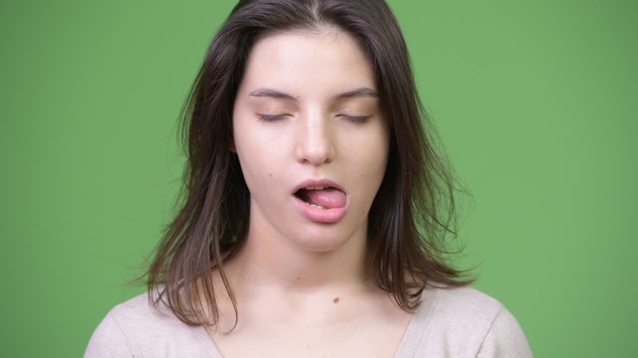 Young beautiful woman looking bored against green background