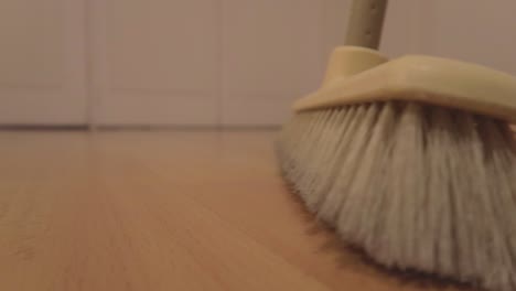 close-up shot of a dirty floor full of dust being swept away by a broom