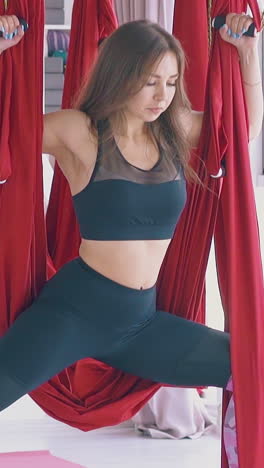 strong ladies group practices modern anti-gravity yoga warrior asana holding special hammocks slow motion