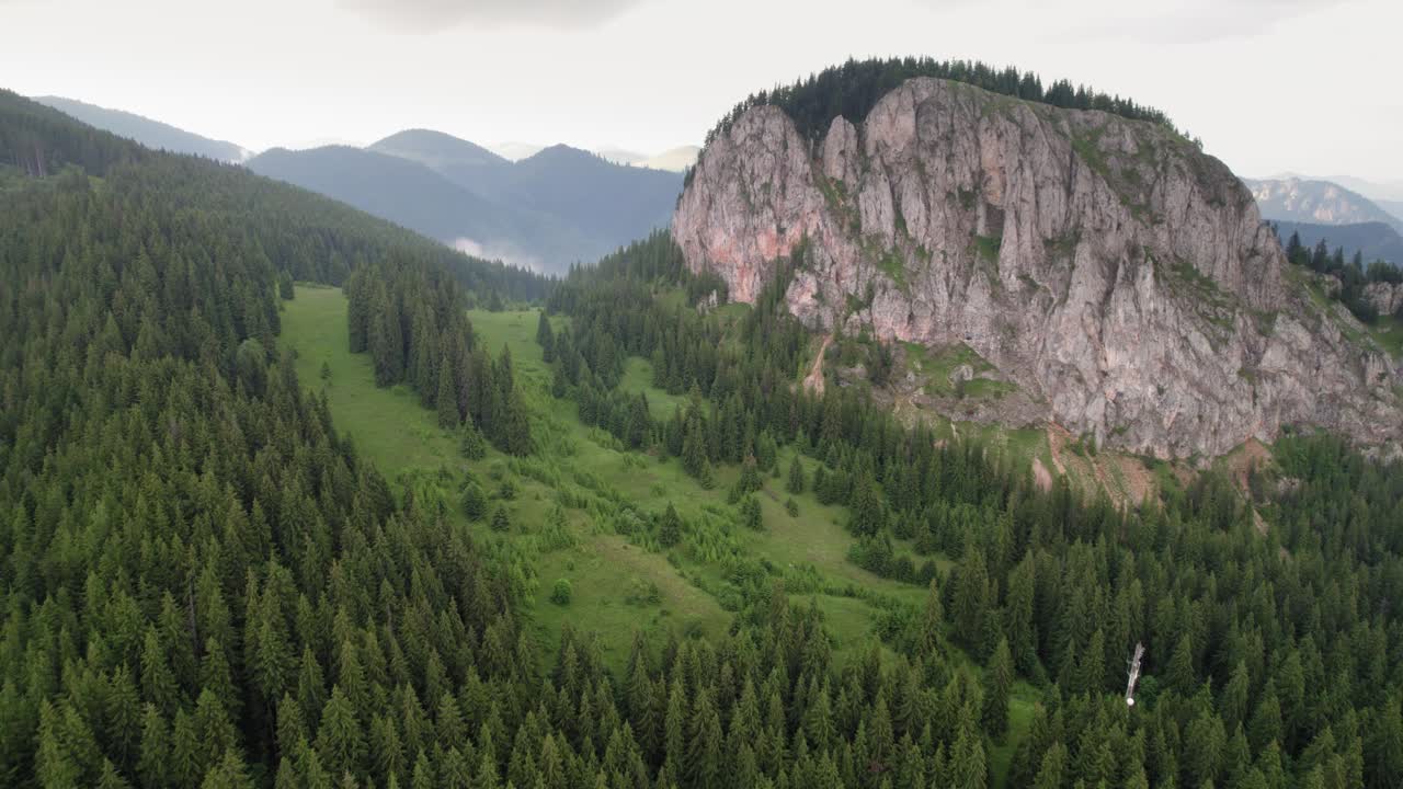 enorme montaña de roca en un valle lleno de árboles, disparo aéreo