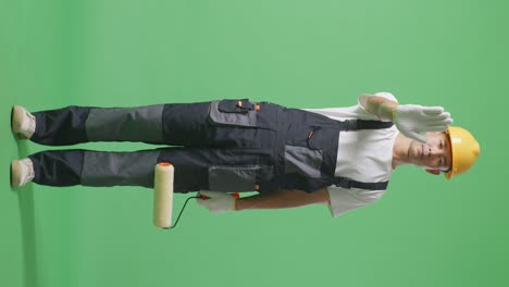 Full Body Of Asian Man Painter Wearing Safety Helmet Looking At Camera And Disapproving With No Hand Sign While Standing In The Green Screen Background Studio