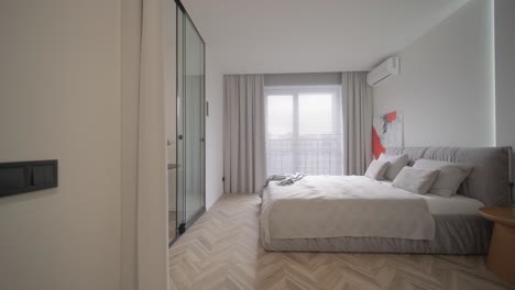 diseño y decoración de interiores de dormitorios modernos con sábanas blancas y grises, silla blanca, cabecera de luz nocturna.