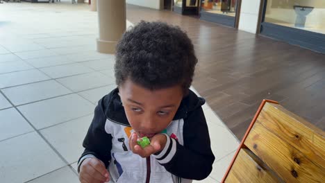 a medium closeup view of a cute biracial black kid absolutly happy eating candies, smiling at the camera.