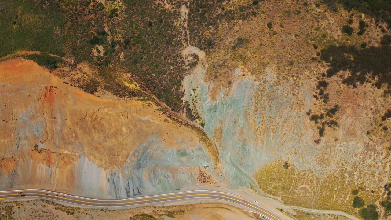 Weird dry landscape covered with moss and lichens. Motorway passing through the bare rocks of California coastline. Aerial view.