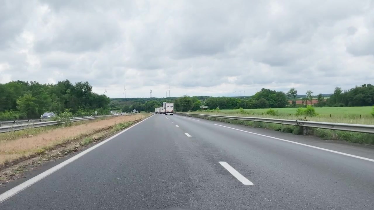 Un camion semirimorchio bianco viaggia lungo un'autostrada asfaltata a più corsie sotto cieli nuvolosi