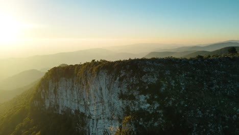 Spectacular-daybreak-with-the-sunlight-shining,-aerial-drone-footage-zooming-towards-the-top-of-a-cliff