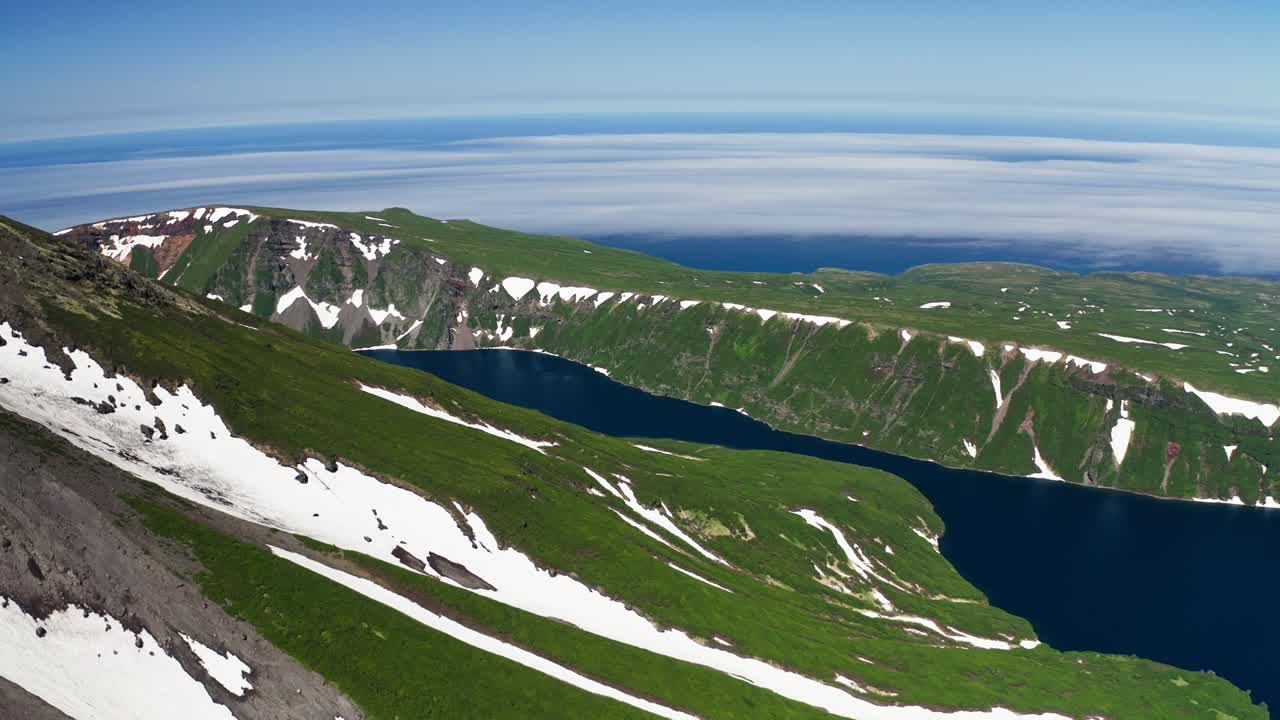 새의 눈 패노라마: 눈이 쌓인 푸른 화산 경사, 파란 물의 호수, 안개가 은 지평선
