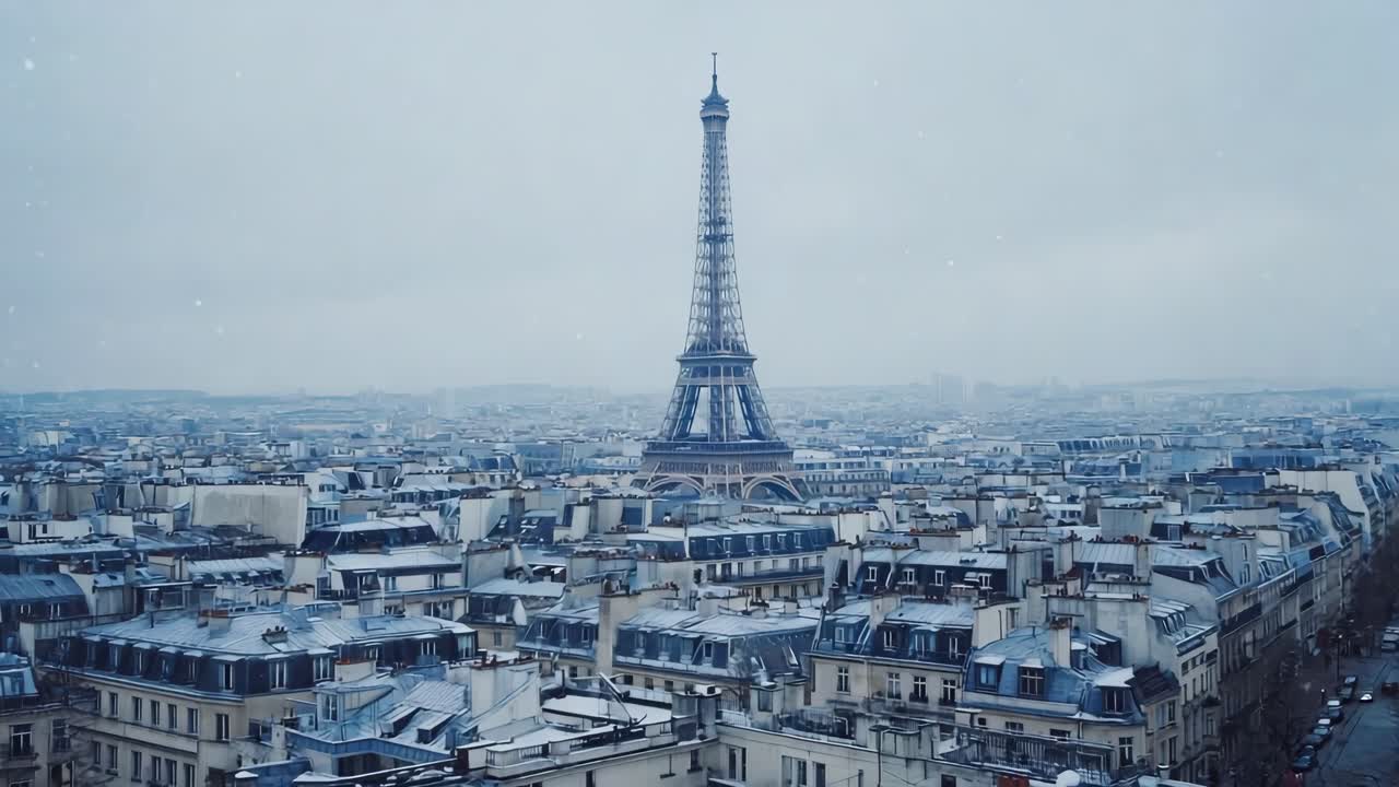 Winter light illuminating iconic Eiffel Tower rising above snow dusted Parisian rooftops, revealing layered architectural landscape under cloudy gray skies