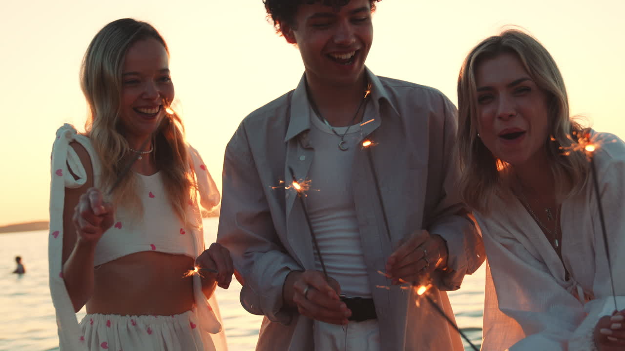 친구들이 스파클러와 함께 해가 지는 해변에서 재미를 느끼고 있습니다.