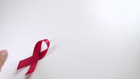 placing a red ribbon on the left side of the frame which signifies the hiv-aids worldwide disease awareness and prevention.