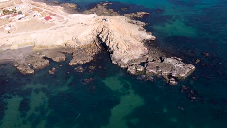 aerial orbit around sea cliffs of mexican coastline with green ocean water