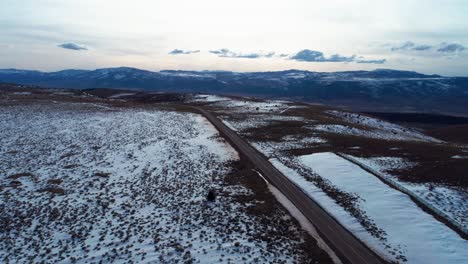 Drohnenaufnahme-Einer-Langen-Und-Geraden-Autobahn-Auf-Einem-Berg-Mit-Schnee