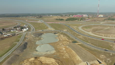 Amplia-Vista-Aérea-De-Un-Gran-Cruce-De-Autopistas-En-Construcción-Con-El-Paisaje-Circundante.