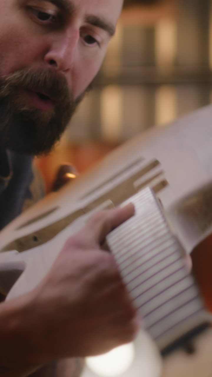 close up Shot of Male Carpenter Fixing Guitar Neck to the Guitar Body Close up Shot of Male Carpenter Fixing Guitar Neck to the Guitar Body after Polishing Woodworking Master Artisan Makes Musical Instrument in Modern Workshop Shot